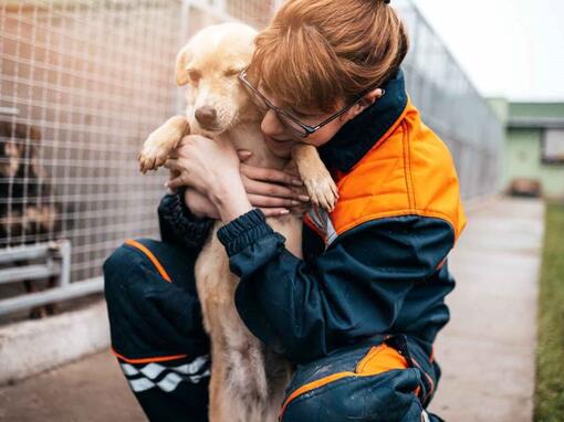 woman hugging dog in kennel